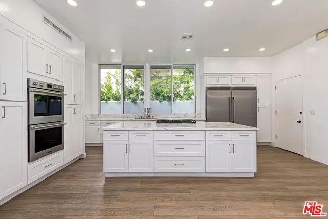 a large kitchen with stainless steel appliances granite countertop a stove a sink and a microwave