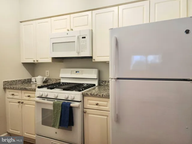 a kitchen with stainless steel appliances white cabinets and a refrigerator