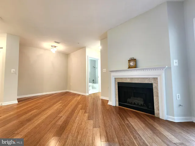 a view of an empty room with wooden floor fireplace and a window