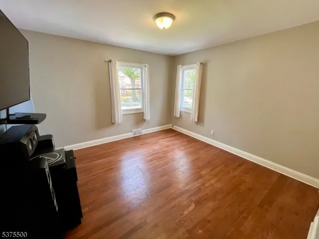 a view of an empty room with wooden floor and stairs