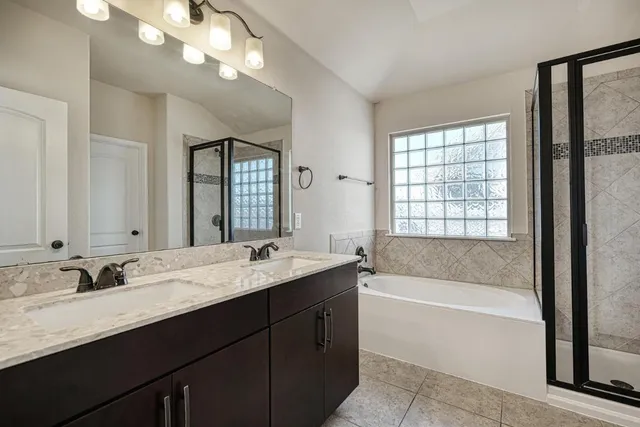 a bath room with a sink vanity tub and a mirror