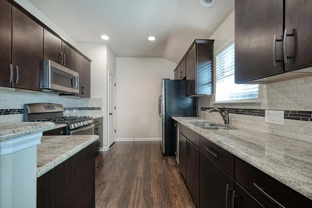 a kitchen with stainless steel appliances granite countertop a sink stove and refrigerator