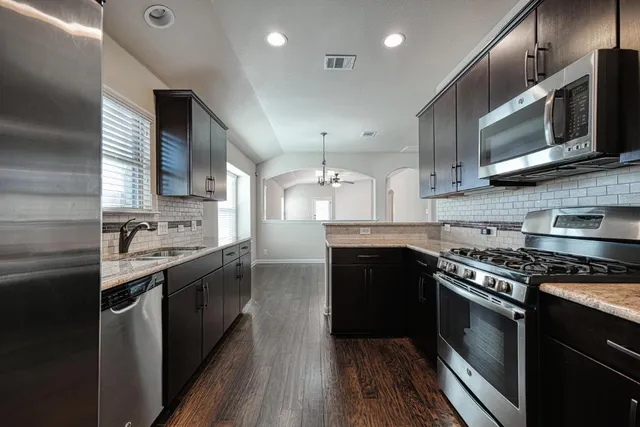 a kitchen with stainless steel appliances granite countertop a stove a sink and a microwave