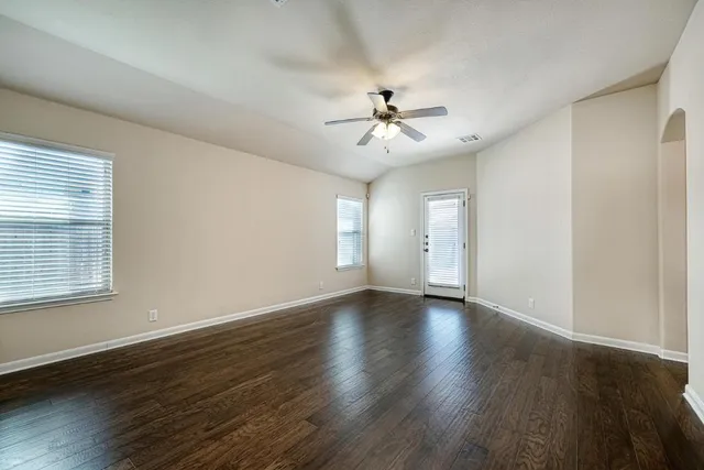 a view of an empty room with a window and wooden floor