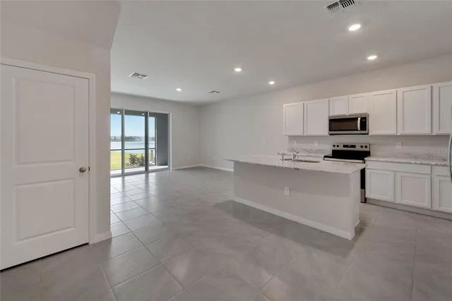 a kitchen with stainless steel appliances granite countertop a refrigerator sink and white cabinets
