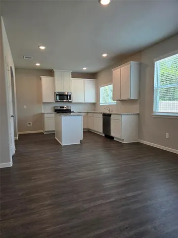a kitchen with a white wooden cabinets and window