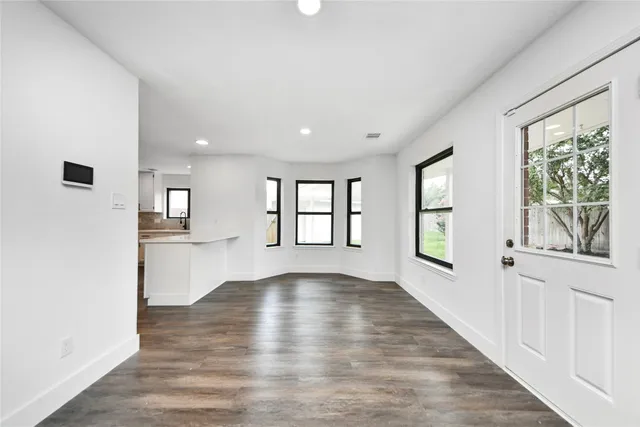 a view of an empty room with a window and wooden floor