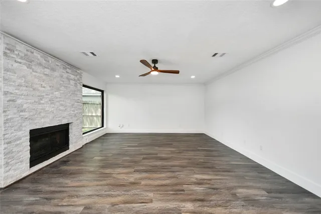 an empty room with wooden floor fireplace and windows