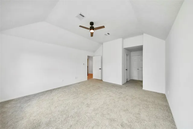 an empty room with a ceiling fan and carpet