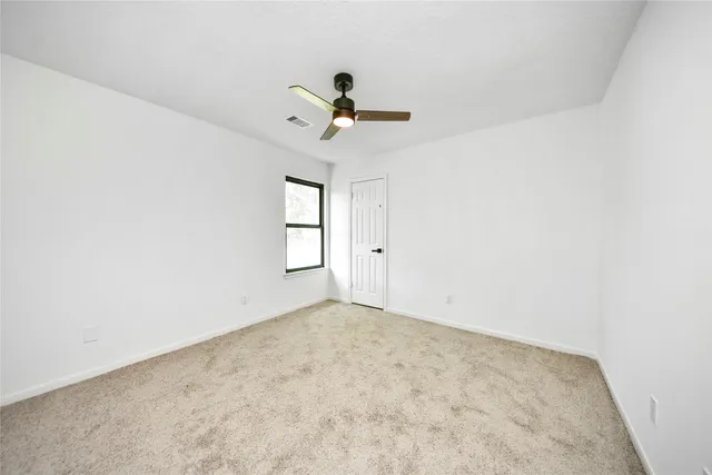 an empty room with windows and ceiling fan view