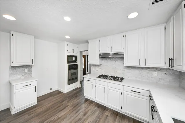 a kitchen with white cabinets and appliances