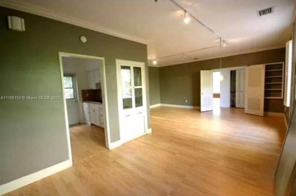 a view of a big room with wooden floor and windows