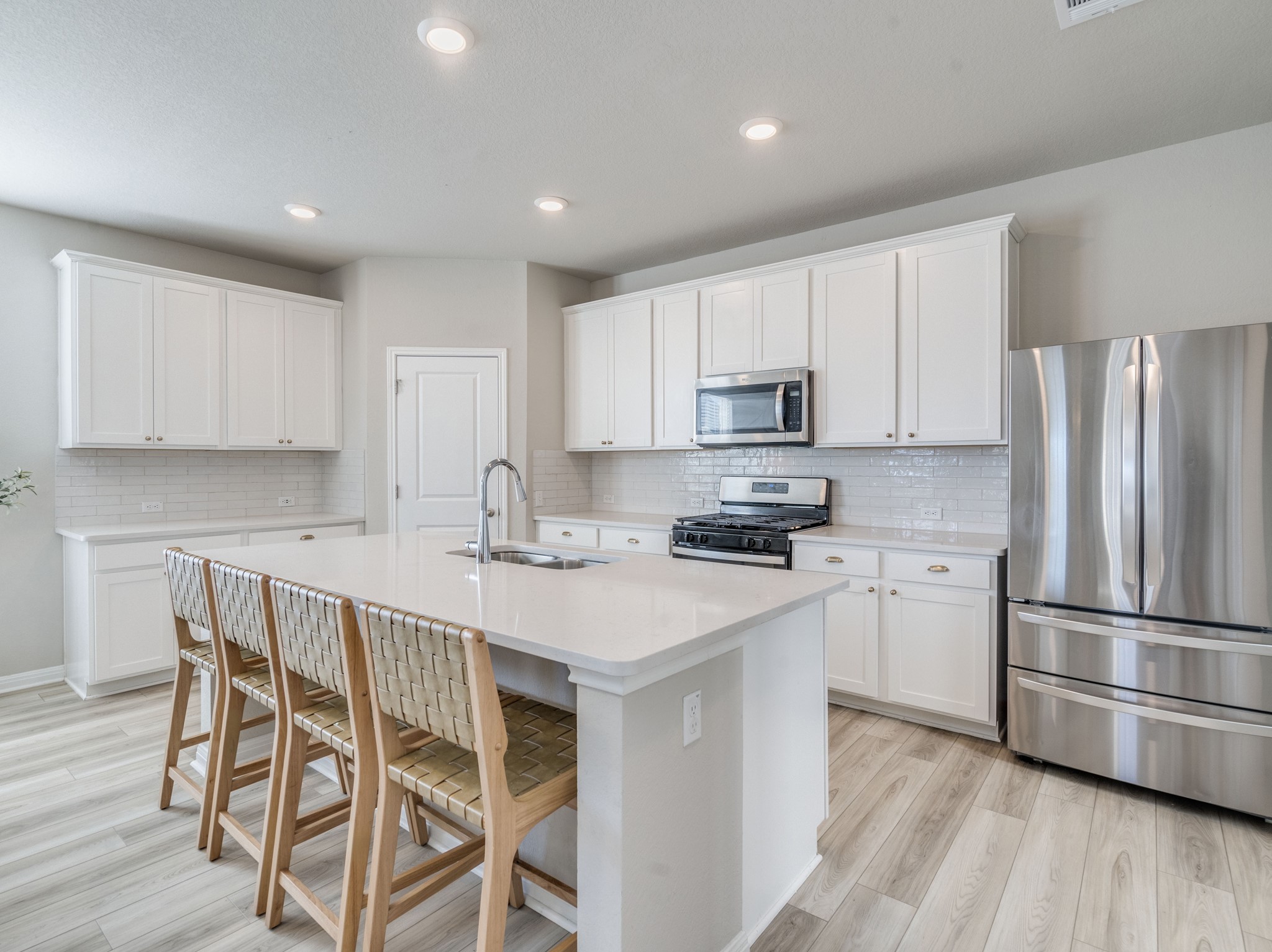 218 Glass Mountain Way Dripping Springs, TX 78620 - Photo 5 of 29 a kitchen with stainless steel appliances granite countertop a refrigerator a stove a sink dishwasher and white cabinets with wooden floor