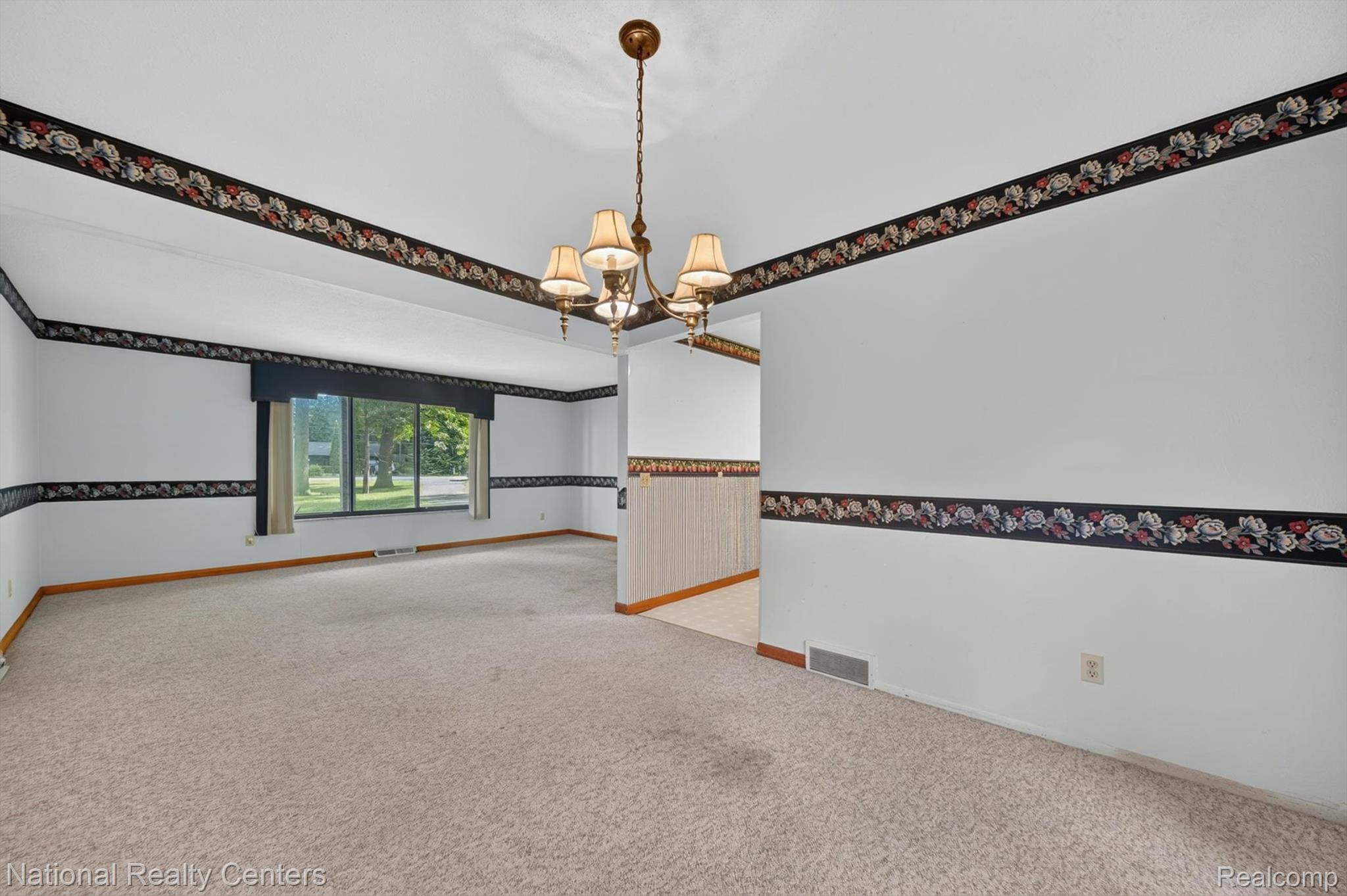 3107 Dean Road Lambertville, MI 48144 - Photo 15 of 45 Spacious carpeted room featuring a large window, a brass-finish chandelier, and decorative wall borders