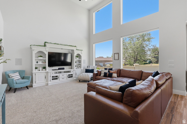 10676 Urban Rdg Cove South Jordan, UT 84095 - Photo 3 of 48 Living area featuring a high vaulted ceiling, large picture windows, light-toned carpeting, built-in media cabinetry, and wood-finish flooring