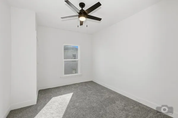 an empty room with a window and a ceiling fan