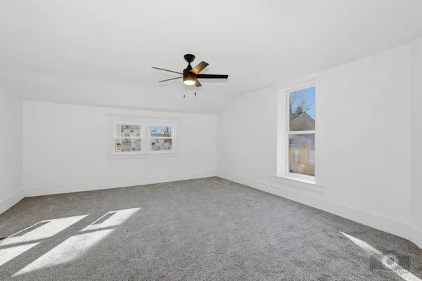 an empty room with windows and fan