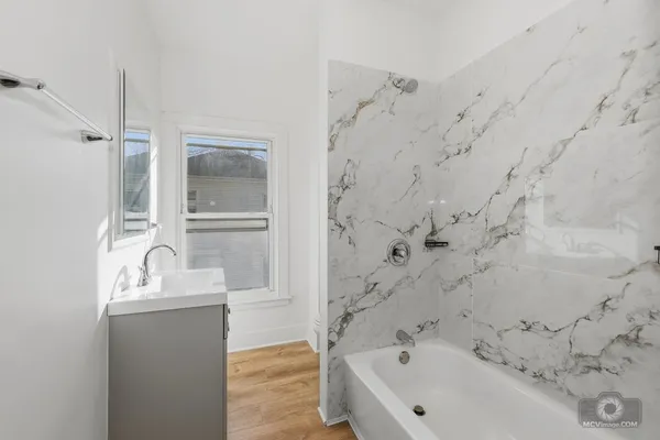 a bathroom with a bathtub sink and mirror