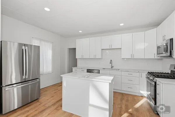 a kitchen with a sink a refrigerator and white cabinets