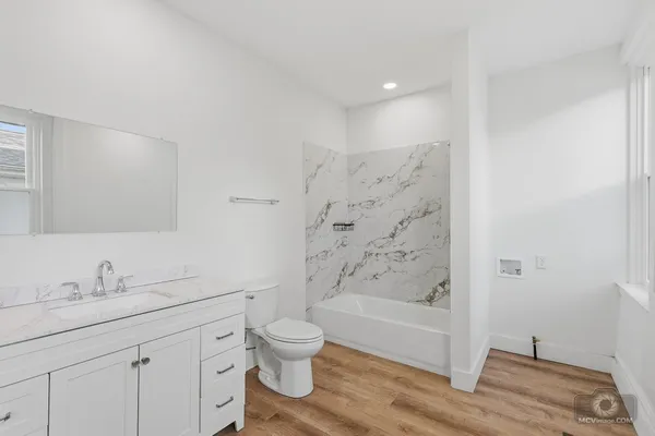 a bathroom with a bathtub shower sink vanity and toilet
