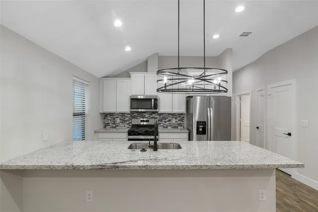 a kitchen with stainless steel appliances granite countertop a sink a stove and a refrigerator