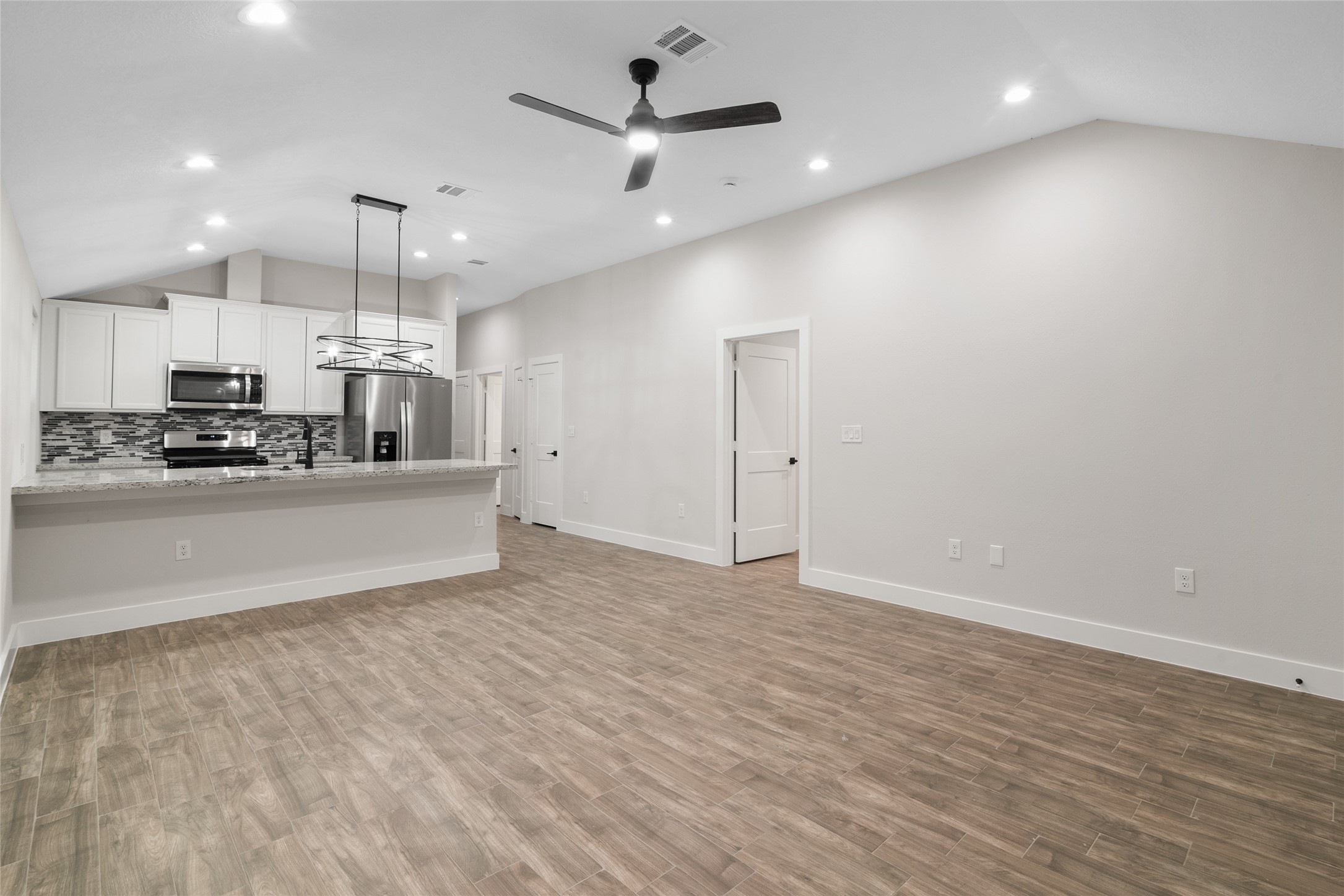 13018 Walden Road, Unit A Montgomery, TX 77356 - Photo 9 of 32 a large white kitchen with kitchen island a stove a sink dishwasher and a refrigerator with wooden floor
