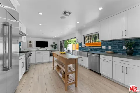 a kitchen with stainless steel appliances granite countertop a refrigerator sink and white cabinets