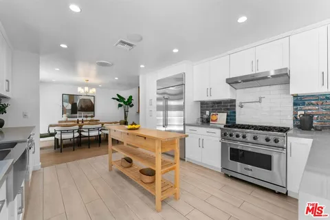 a kitchen with stainless steel appliances a stove a sink dishwasher a oven with white cabinets and wooden floor