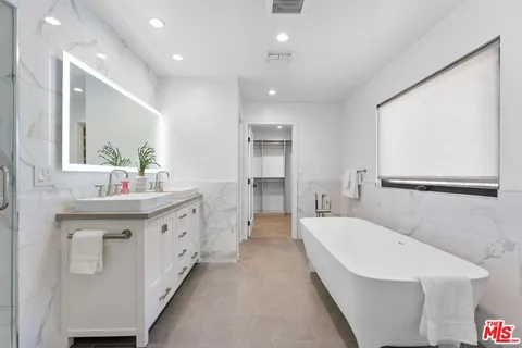 a bathroom with a double vanity sink a mirror and a bathtub
