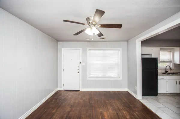 an empty room with wooden floor closet chandelier fan and windows