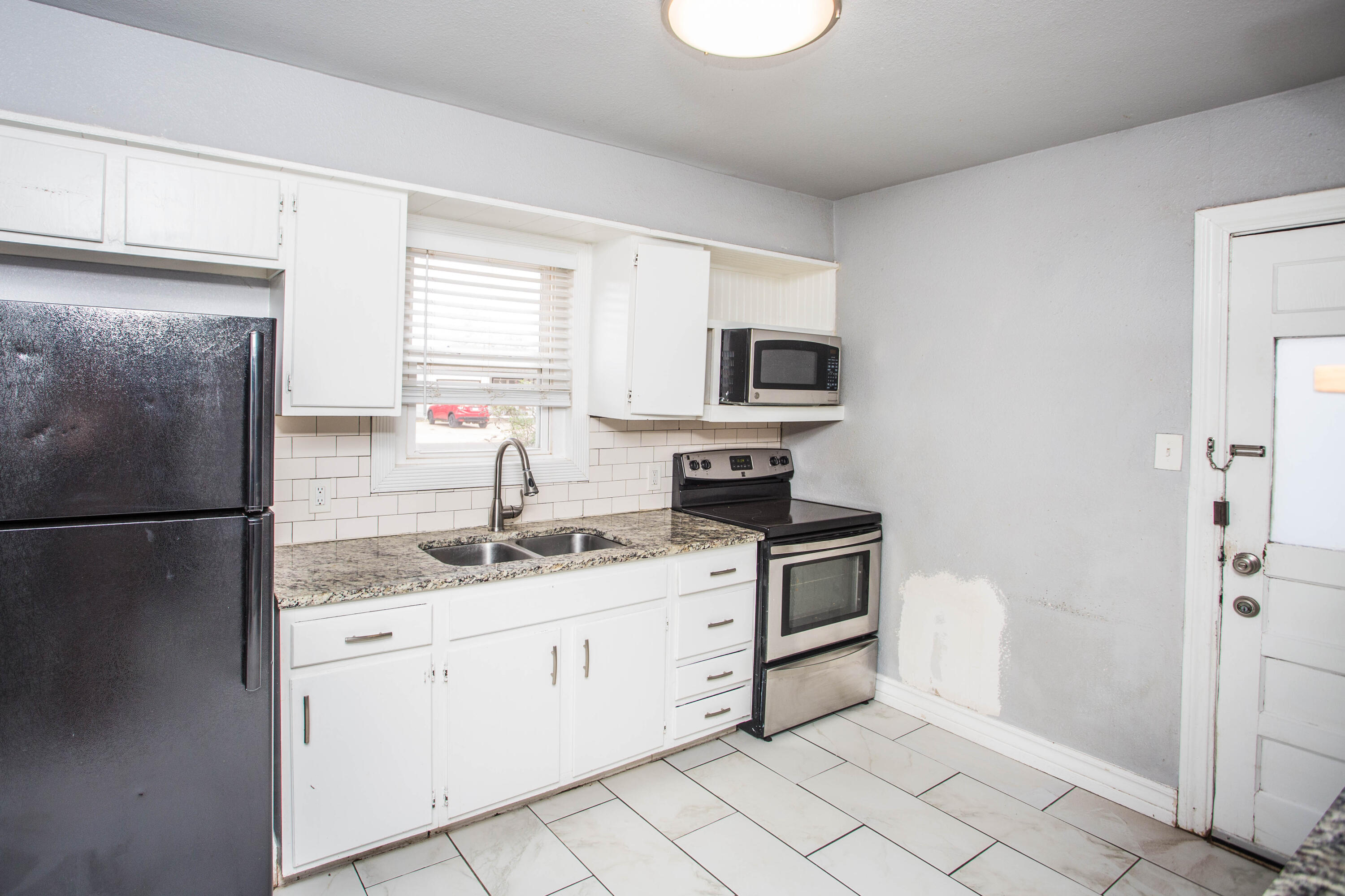 2409 39th Street Lubbock, TX 79412 - Photo 5 of 16 a kitchen with stainless steel appliances granite countertop a refrigerator sink and stove