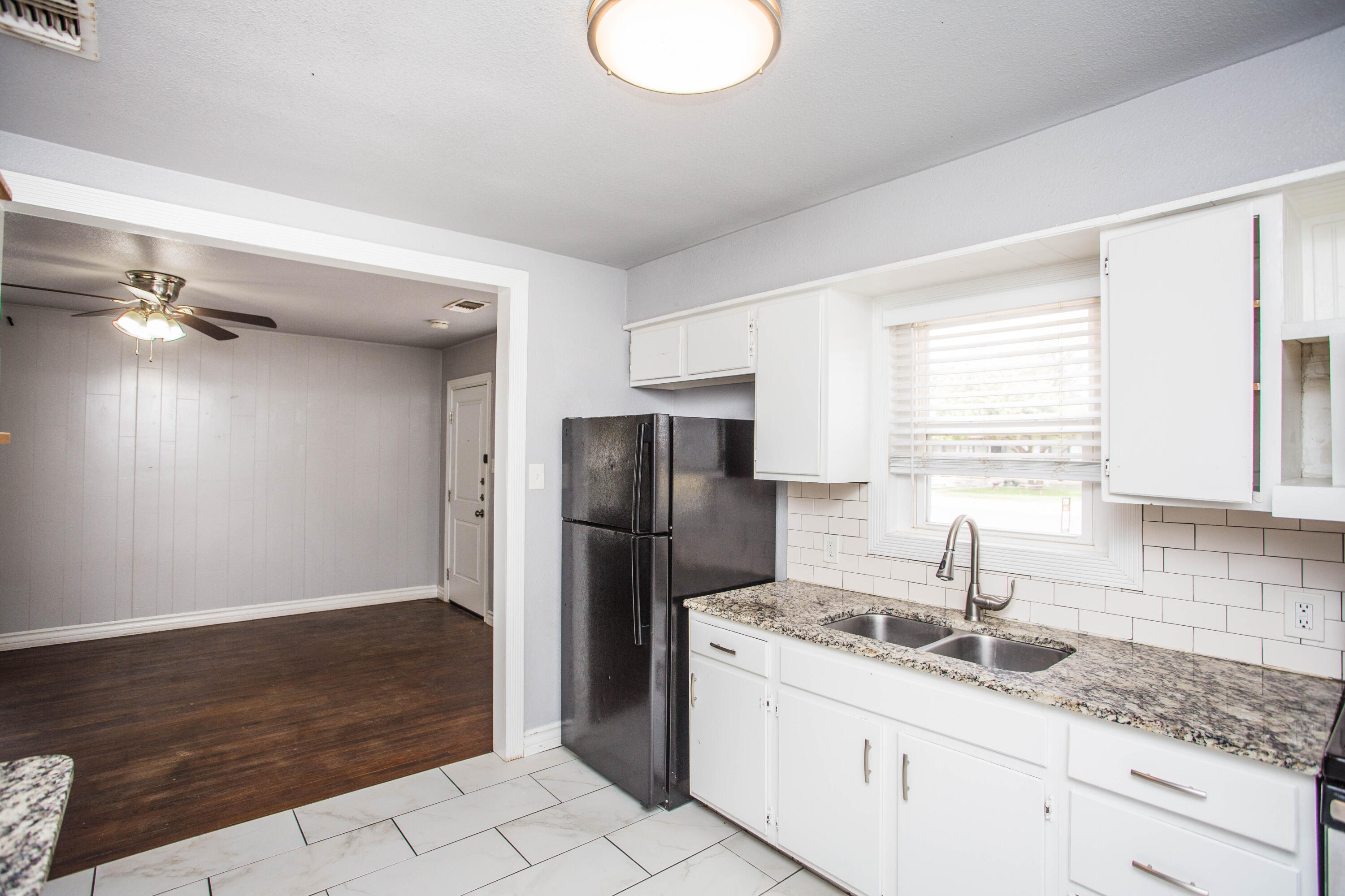 2409 39th Street Lubbock, TX 79412 - Photo 6 of 16 a kitchen with a sink a refrigerator and cabinets