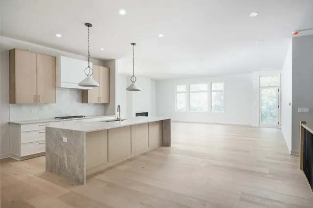 a large kitchen with stainless steel appliances kitchen island granite countertop a stove a sink a refrigerator and white cabinets with wooden floor
