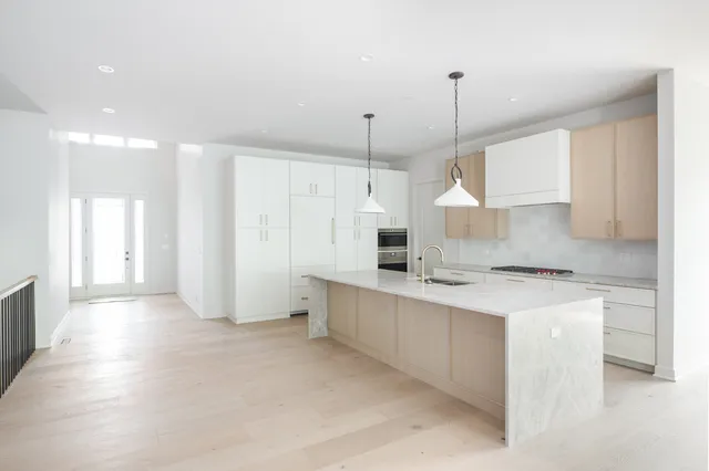 a kitchen with stainless steel appliances kitchen island granite countertop a sink a stove a refrigerator and white cabinets