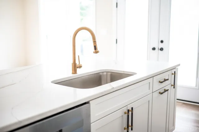 a kitchen with stainless steel appliances a refrigerator a sink a stove and white cabinets