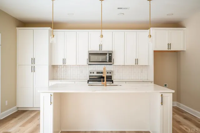 a kitchen with kitchen island a sink a stove a refrigerator and white cabinets