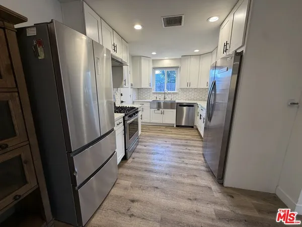 a kitchen with stainless steel appliances a refrigerator and wooden floor