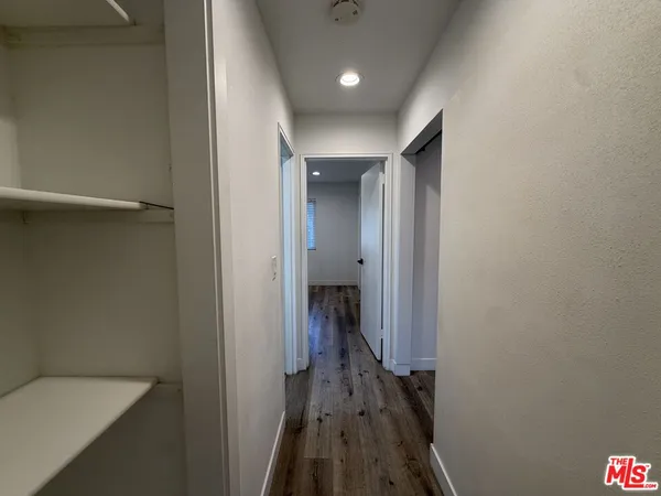a view of a hallway with wooden floor and a bathroom