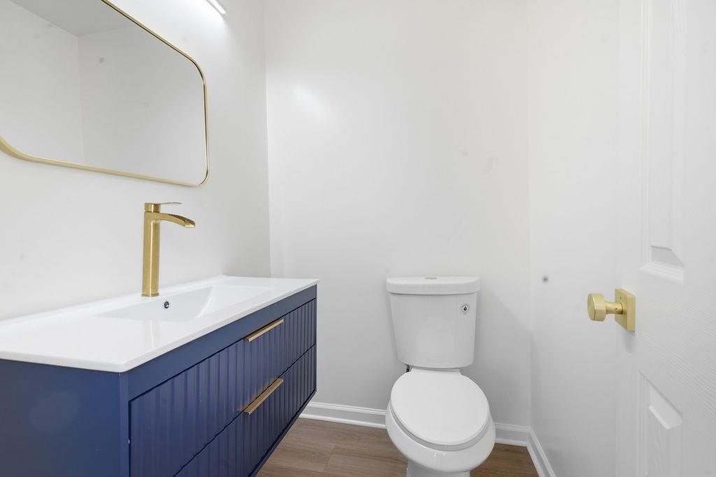 1304 Winfield Road Memphis, TN 38116 - Photo 15 of 19 Floating vanity with a gold-finish faucet, rectangular mirror, and wood-finish flooring