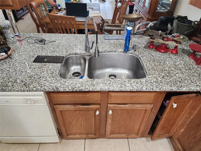 a kitchen with kitchen island granite countertop a sink a counter top space and cabinets