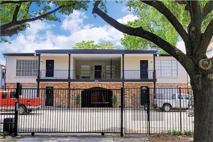 415 Hawthorne Street, Unit 4 Houston, TX 77006 - Photo 2 of 7 Brick and siding exterior, featuring upper-level balconies. A gated entry provides security, and the property is surrounded by mature trees, creating a welcoming atmosphere.