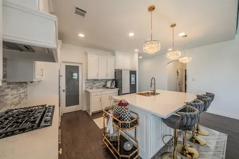 a open kitchen with stainless steel appliances granite countertop a stove a refrigerator a oven a dining table and chairs with wooden floor