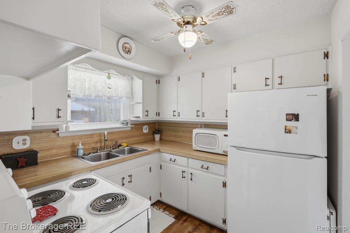 613 East Atherton Road Flint, MI 48507 - Photo 11 of 42 White cabinetry with dark hardware, wood-finish countertops, and a dual basin stainless steel sink