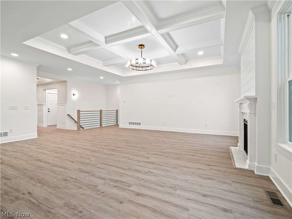 32 Brookside Lane North Ridgeville, OH 44039 - Photo 24 of 50 Unfurnished living room with a chandelier, coffered ceiling, light wood-type flooring, beamed ceiling, and recessed lighting