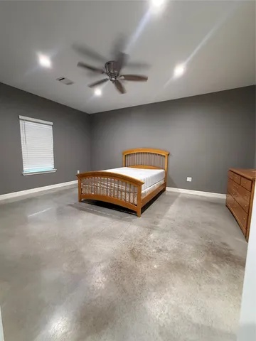 an empty room with windows and ceiling fan