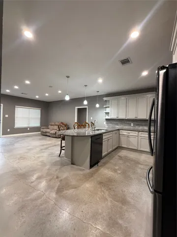 a large white kitchen with kitchen island a sink a counter and chairs