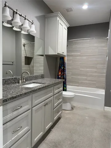 a bathroom with a granite countertop toilet a sink and a bathtub