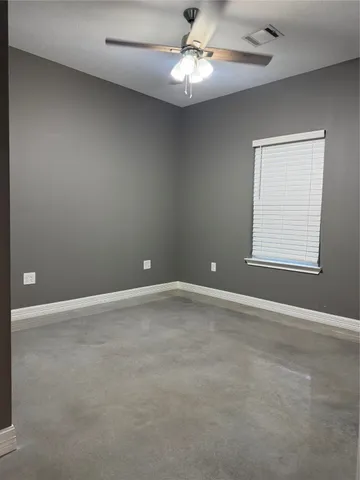 an empty room with a window and ceiling fan