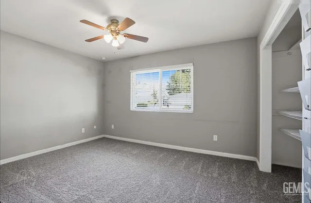 an empty room with a ceiling fan and window