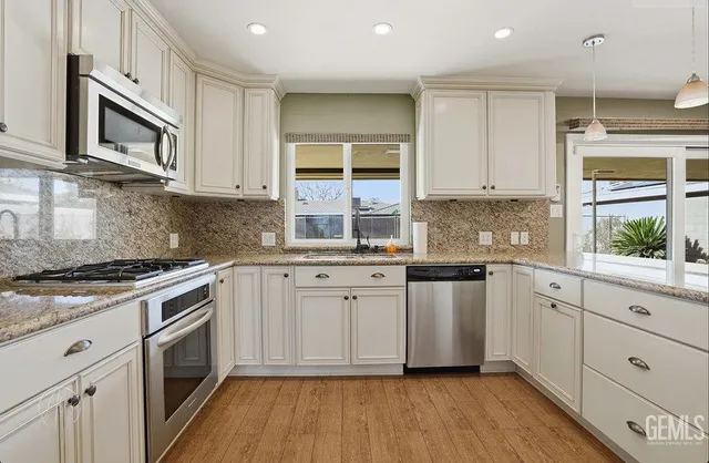 a kitchen with stainless steel appliances granite countertop a stove a sink and a microwave